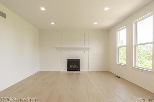 unfurnished living room with light wood finished floors, a fireplace, baseboards, visible vents, and recessed lighting