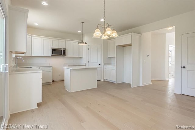 kitchen featuring light wood-style flooring, a center island, a sink, stainless steel microwave, and recessed lighting