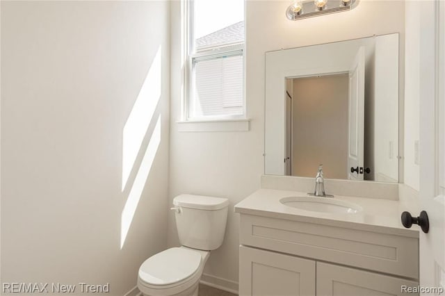 bathroom featuring toilet, vanity, and baseboards