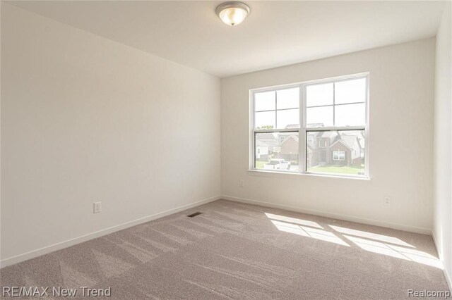 carpeted spare room featuring baseboards