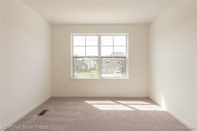 spare room featuring baseboards, visible vents, and carpet floors