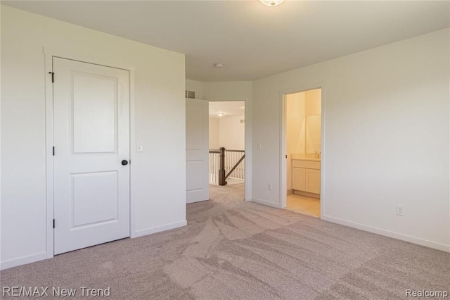 unfurnished bedroom with carpet floors, ensuite bath, and baseboards