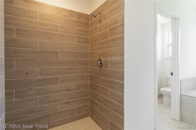 full bathroom with a tile shower, toilet, and tile patterned floors