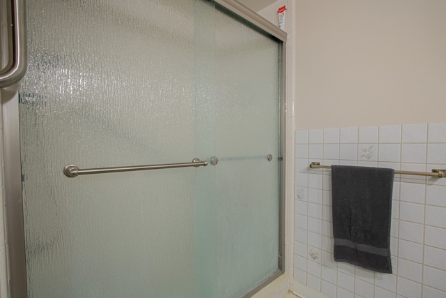 bathroom with a stall shower and tile walls