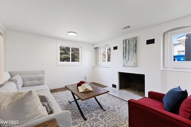 living room with visible vents, wood finished floors, and a fireplace with flush hearth