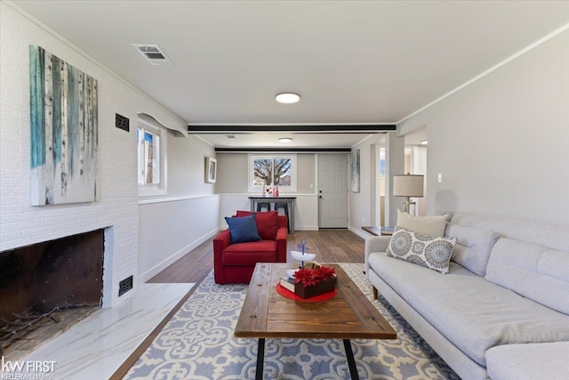 living area featuring wood finished floors, visible vents, and a fireplace