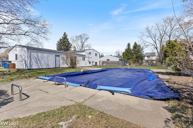 view of swimming pool featuring a patio, fence, and a covered pool