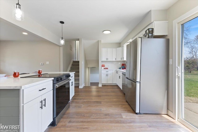 kitchen with light countertops, light wood-style flooring, appliances with stainless steel finishes, and white cabinetry