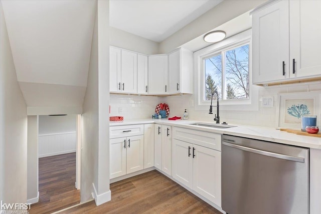 kitchen with white cabinets, stainless steel dishwasher, a sink, and light wood-style floors