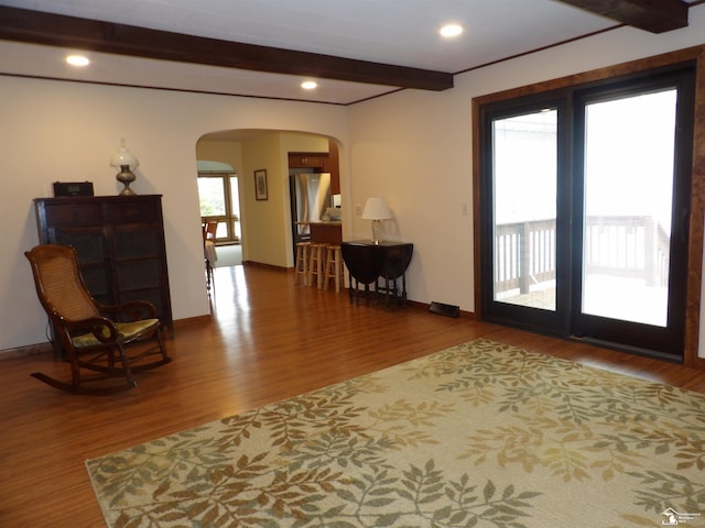 interior space featuring recessed lighting, wood finished floors, arched walkways, beam ceiling, and baseboards