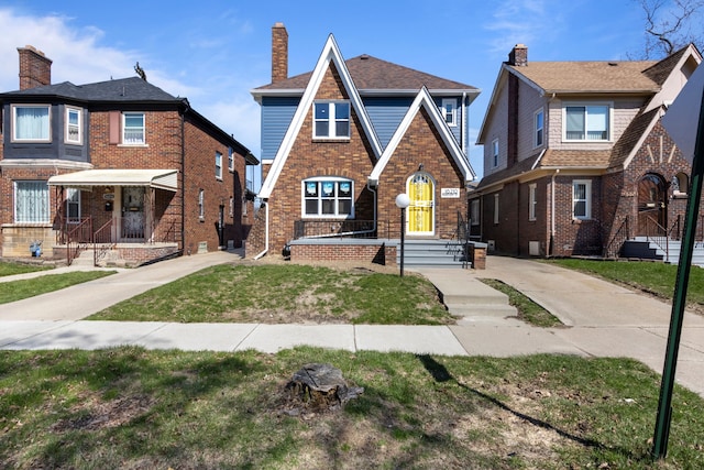 tudor home featuring brick siding and a front yard