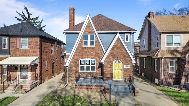 tudor home featuring brick siding and a chimney