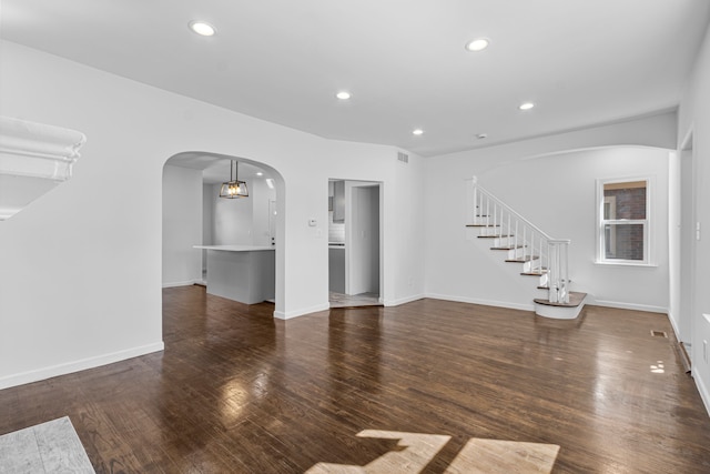 unfurnished living room with recessed lighting, wood finished floors, visible vents, arched walkways, and stairs