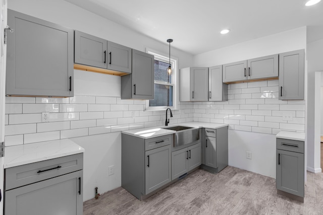 kitchen featuring tasteful backsplash, gray cabinetry, and a sink