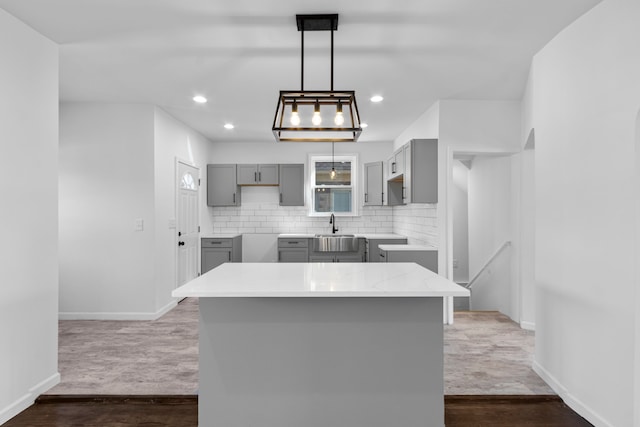 kitchen with a center island, dark wood finished floors, tasteful backsplash, baseboards, and gray cabinets