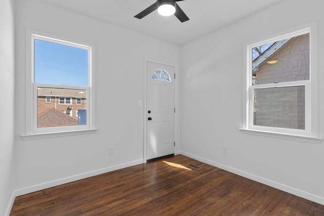 foyer featuring ceiling fan, visible vents, baseboards, and dark wood-style flooring