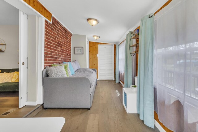 interior space with brick wall, hardwood / wood-style floors, visible vents, and a closet