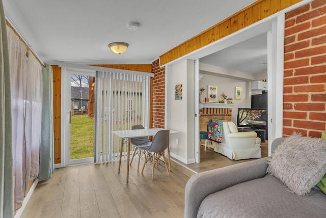 interior space featuring light wood-style floors, baseboards, and brick wall