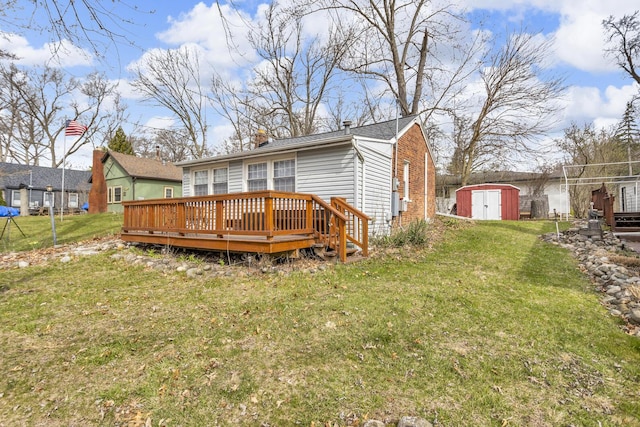 rear view of property with a lawn, a wooden deck, an outbuilding, and a shed