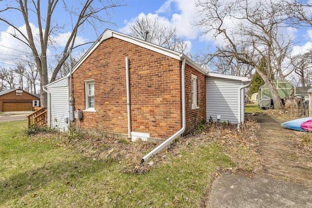 view of side of property featuring brick siding and an outbuilding