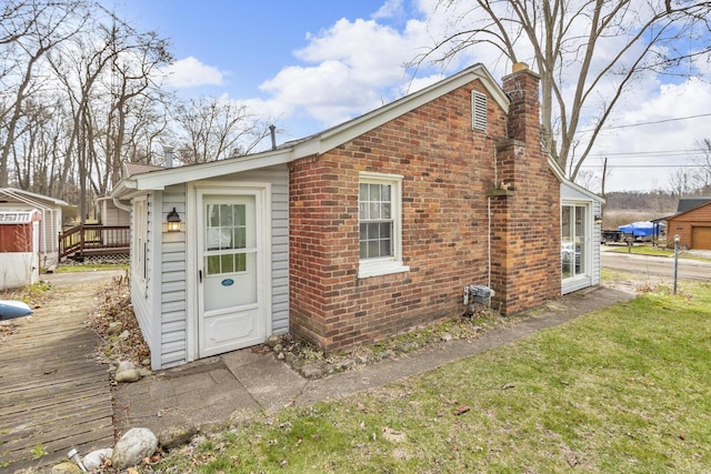 exterior space with a chimney, a wooden deck, brick siding, and a yard