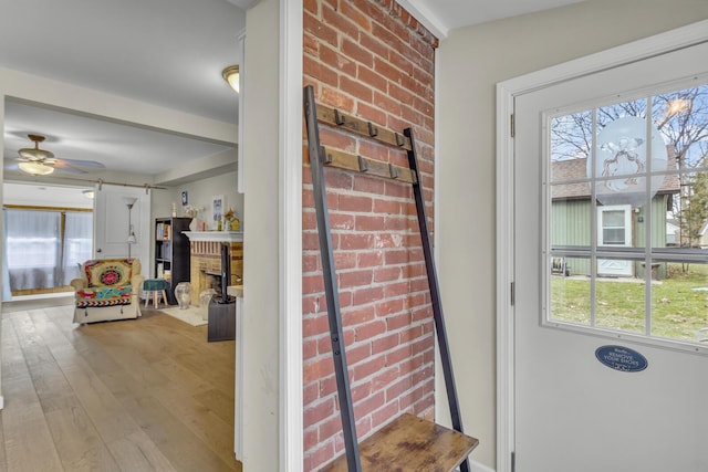 interior space featuring a fireplace, wood finished floors, a healthy amount of sunlight, and ceiling fan