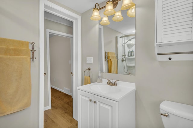bathroom featuring toilet, visible vents, wood finished floors, a shower, and vanity