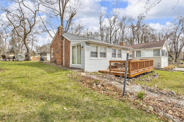 back of house with a wooden deck, a lawn, and a chimney