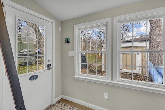 entryway featuring baseboards, vaulted ceiling, and plenty of natural light