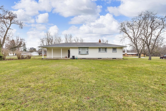 back of property featuring a lawn, crawl space, and a chimney