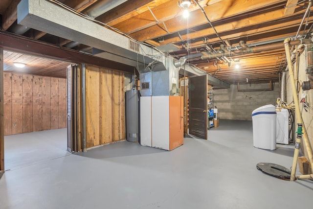 unfinished basement featuring water heater, wooden walls, and visible vents