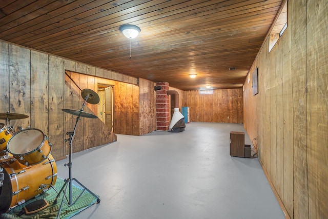 finished basement featuring wooden walls, wooden ceiling, and a wood stove
