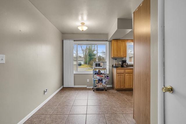 kitchen featuring baseboards, white microwave, and light tile patterned floors