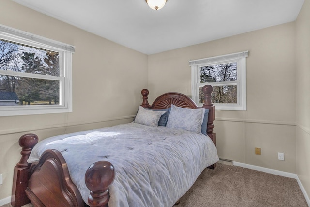 carpeted bedroom with a baseboard radiator, baseboards, and multiple windows