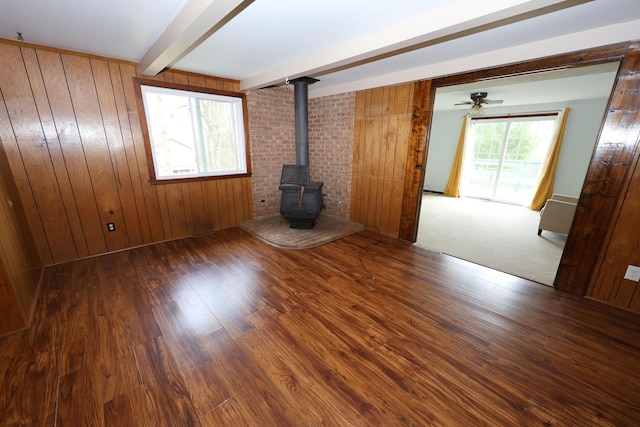 69369 Oak St, Benton Harbor, MI 49022 - unfurnished living room with a wood stove, wooden walls, beam ceiling, and wood finished floors