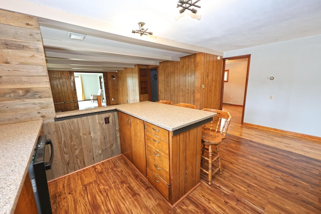 69369 Oak St, Benton Harbor, MI 49022 - kitchen featuring brown cabinetry, a kitchen breakfast bar, baseboards, and wood finished floors