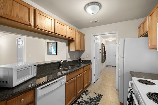 52140 Naugatuck Dr, Macomb, MI 48042 - kitchen with brown cabinetry, visible vents, a sink, dark stone countertops, and white appliances