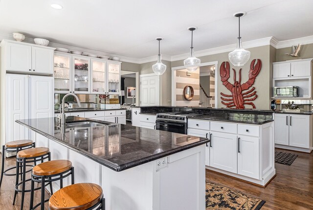 975 Pine Needle Trl, Rochester, MI 48306 - kitchen with a spacious island, stainless steel microwave, gas range oven, dark wood-type flooring, and crown molding