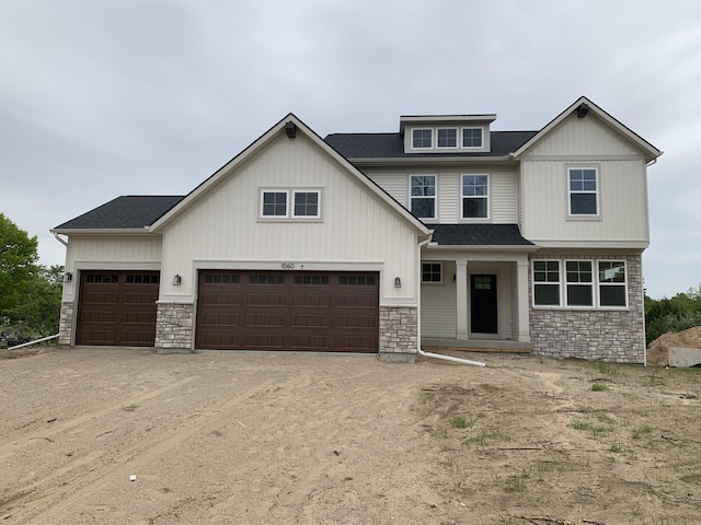 1060 N Wahington St, Lowell, MI 49331 - view of front of house with stone siding, a shingled roof, driveway, and a garage