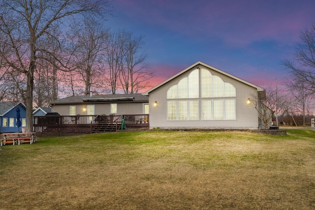 rear view of property featuring a deck and a lawn