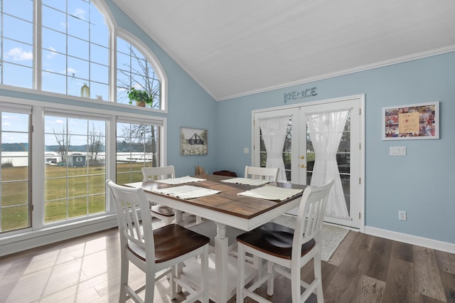 dining area featuring baseboards, french doors, crown molding, high vaulted ceiling, and wood finished floors
