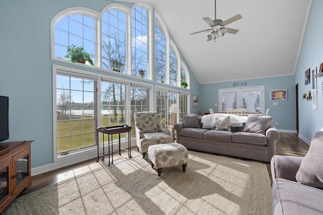 living room with baseboards, ornamental molding, ceiling fan, wood finished floors, and high vaulted ceiling