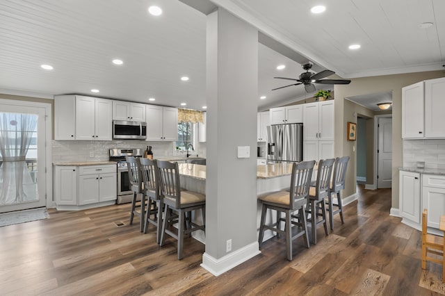 kitchen featuring backsplash, baseboards, appliances with stainless steel finishes, and a breakfast bar