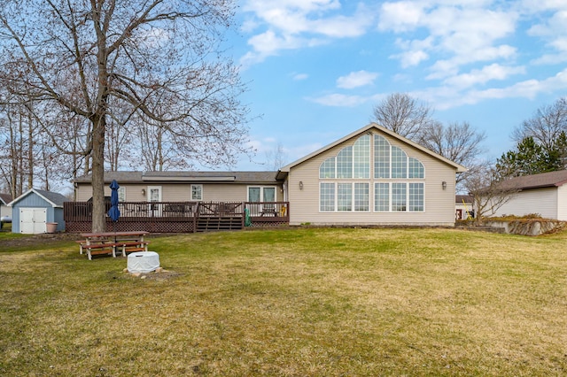 back of property featuring a yard, a deck, an outdoor structure, and a storage unit