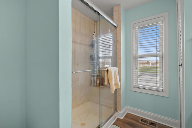 full bathroom featuring a shower stall, visible vents, baseboards, and wood finished floors
