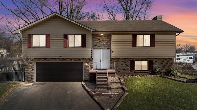 20100 Wick Rd, Taylor, MI 48180 - split foyer home with a front lawn, a chimney, brick siding, an attached garage, and aphalt driveway