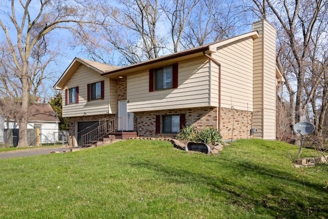 20100 Wick Rd, Taylor, MI 48180 - split foyer home with a chimney, aphalt driveway, an attached garage, brick siding, and a front yard