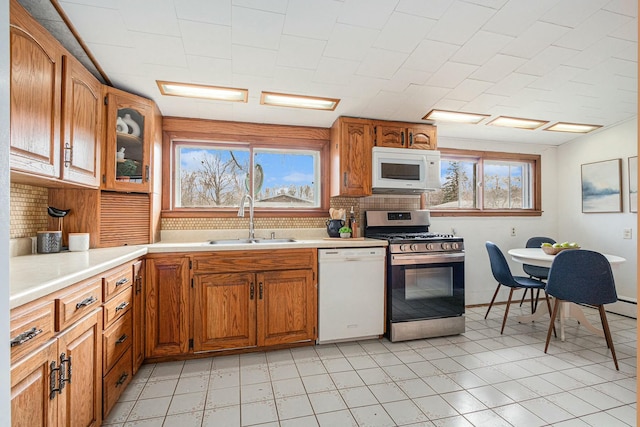 kitchen featuring decorative backsplash, a wealth of natural light, a sink, and white appliances