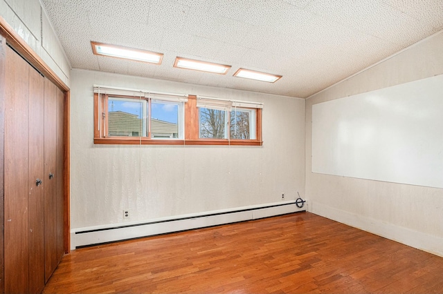 unfurnished room featuring a baseboard heating unit and wood finished floors