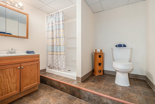 bathroom with baseboards, toilet, a drop ceiling, and a stall shower